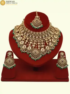 Traditional matte gold necklace set with ruby stones, green beads, intricate carvings, earrings, and maang tikka displayed on red stand, Ishwar Arts and Crafts