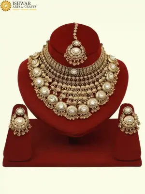 Heavy matte gold brass bridal necklace set with kundan stones, earrings, and maang tikka displayed on red jewelry stand, Ishwar Arts and Crafts