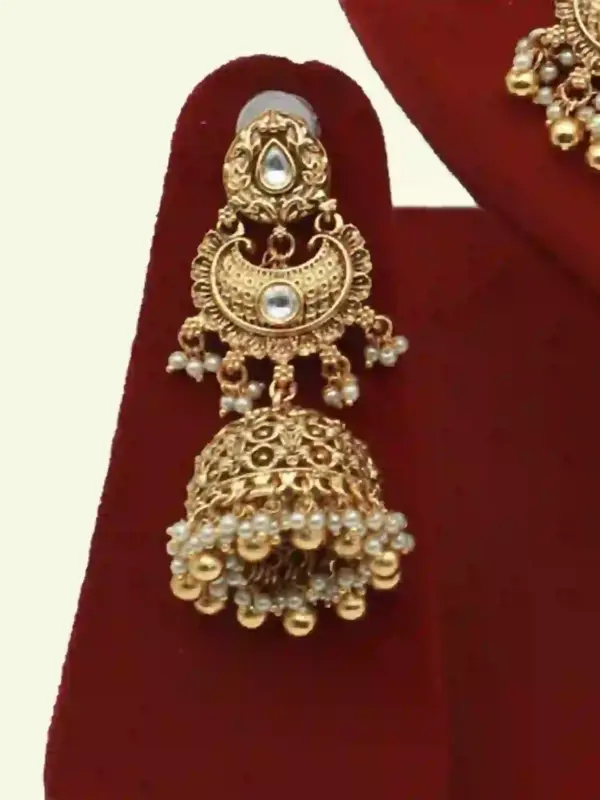 Antique gold bridal necklace set with hanging beads, matching jhumka earrings, and maangtika on red display stand