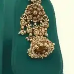 Antique gold intricate carving bridal necklace set with matching heavy earrings and maang tikka displayed on green jewelry stand