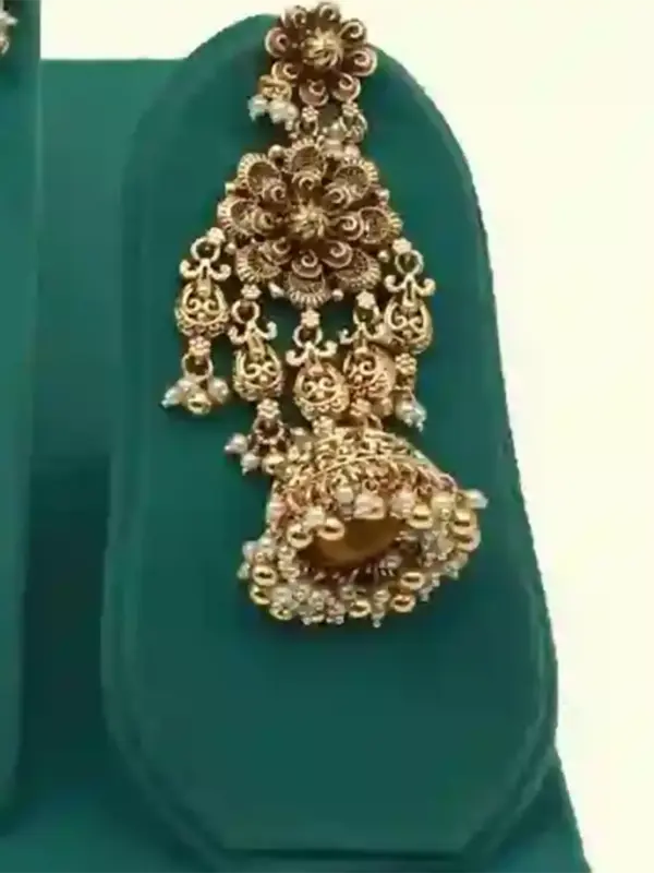 Antique gold intricate carving bridal necklace set with matching heavy earrings and maang tikka displayed on green jewelry stand