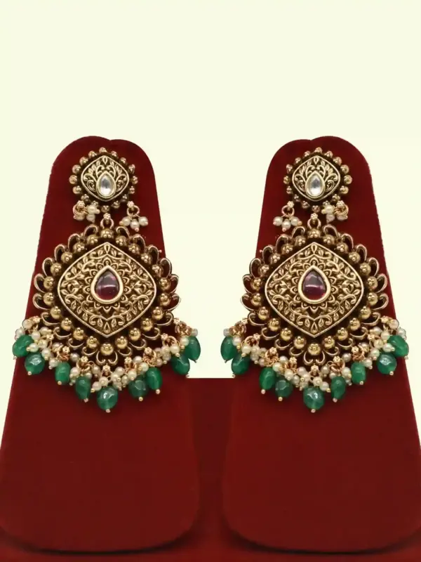 Traditional matte gold necklace set with ruby stones, green beads, intricate carvings, earrings, and maang tikka displayed on red stand, Ishwar Arts and Crafts