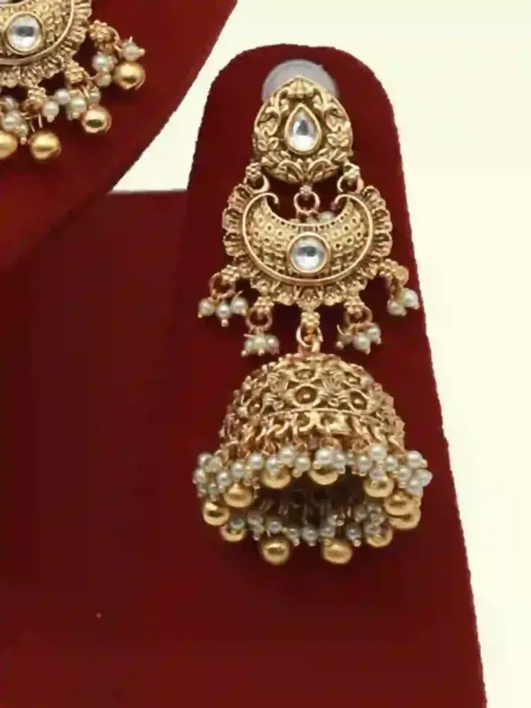 Antique gold bridal necklace set with hanging beads, matching jhumka earrings, and maangtika on red display stand