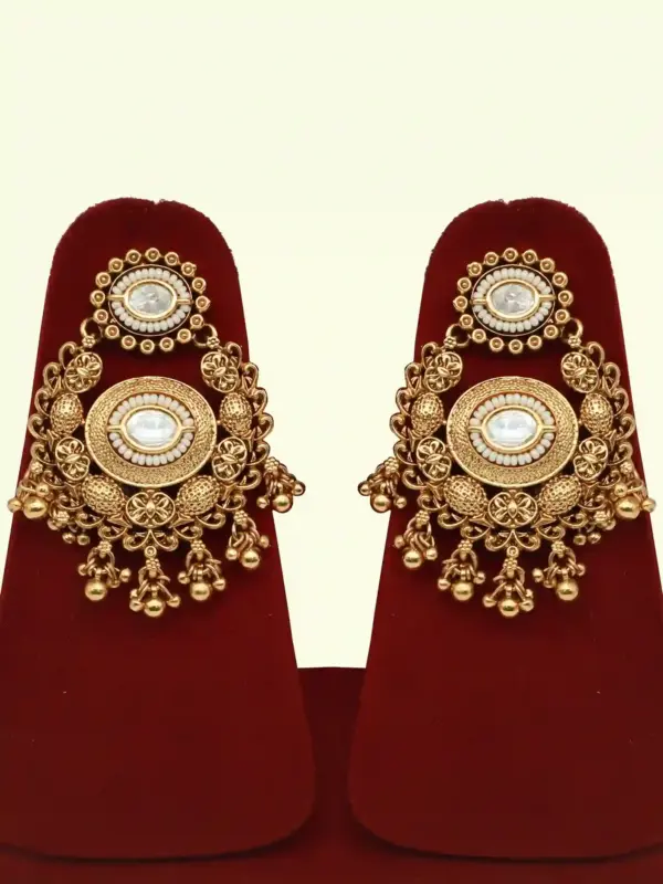 Heavy matte gold brass bridal necklace set with kundan stones, earrings, and maang tikka displayed on red jewelry stand