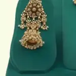 Antique gold intricate carving bridal necklace set with matching heavy earrings and maang tikka displayed on green jewelry stand