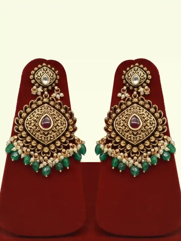 Traditional matte gold necklace set with ruby stones, green beads, intricate carvings, earrings, and maang tikka displayed on red stand