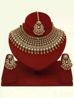 Antique gold brass bridal necklace set with Kundan stones, matching earrings, and maangtika on red display, Ishwar Arts and Crafts